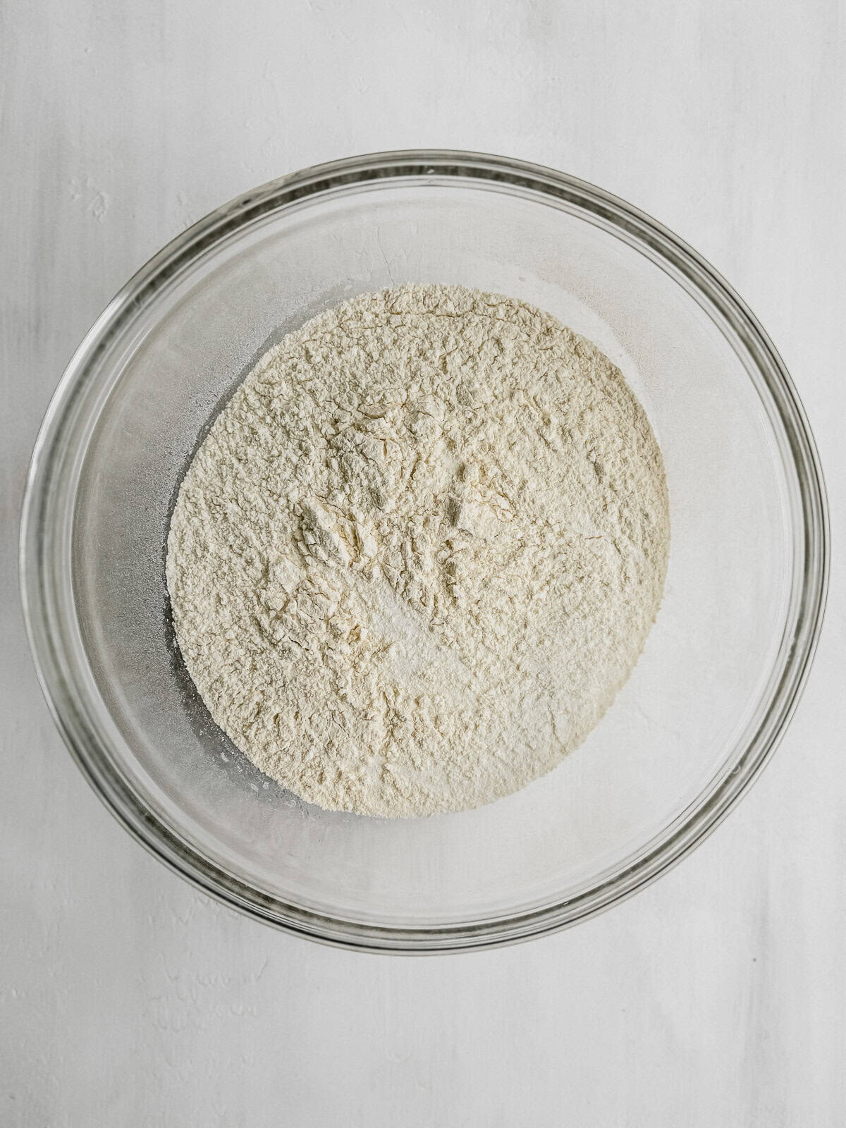 A large mixing bowl with sifted flour, sugar, ground cinnamon, and salt.