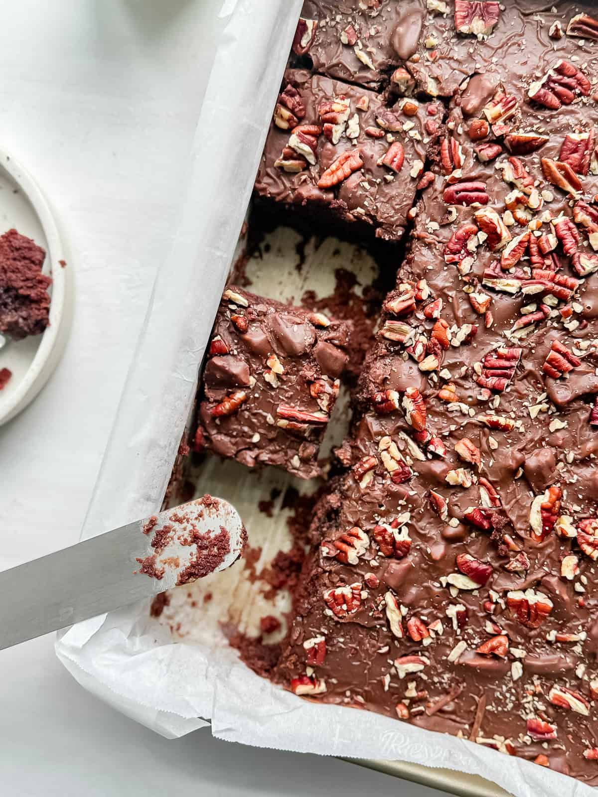 Sliced Texas sheet cake in a cake pan with an offset spatula.