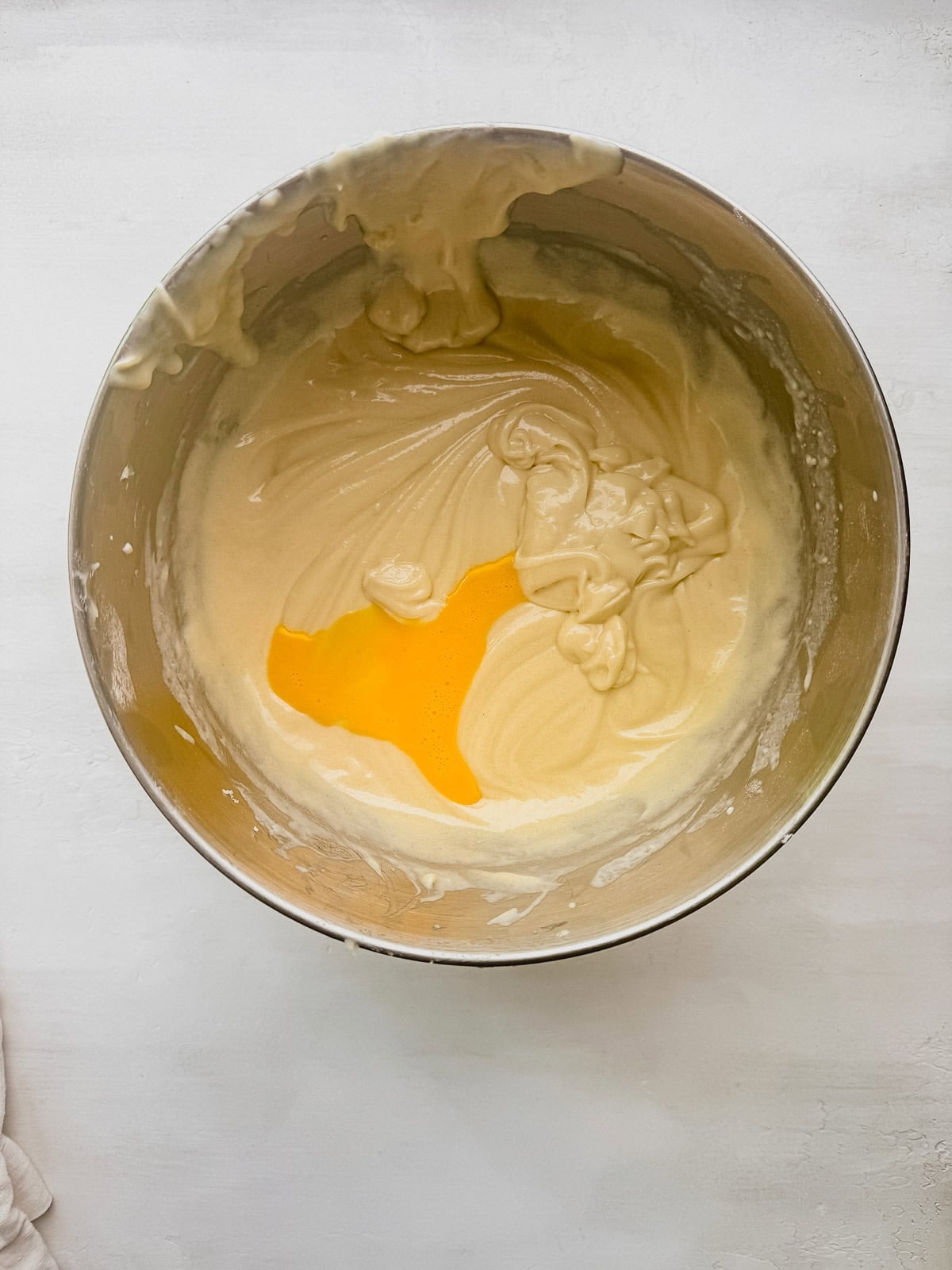 Egg mixture being added to the cake batter in a mixing bowl.