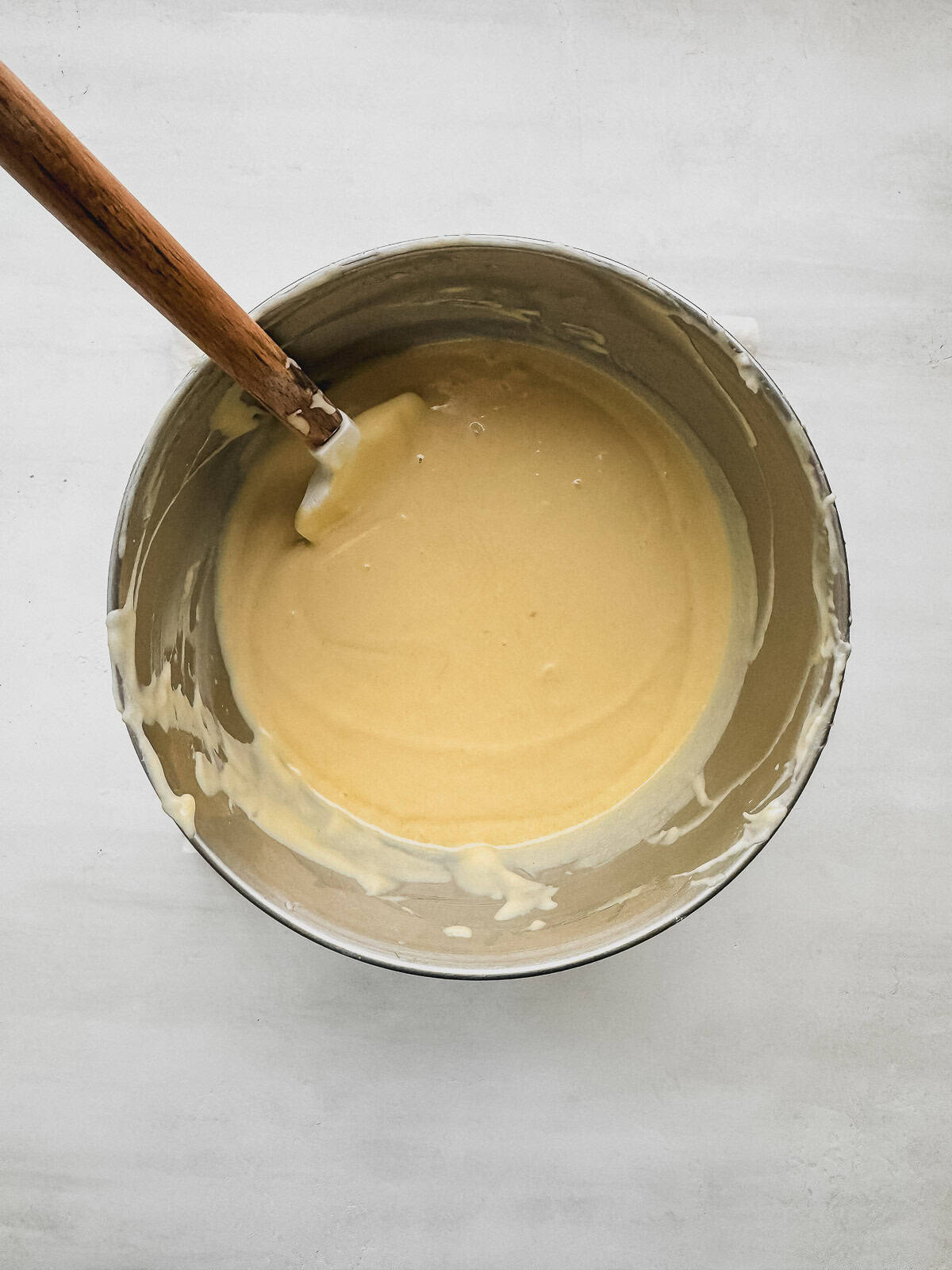 Vanilla cake batter in a mixing bowl with a rubber spatula.