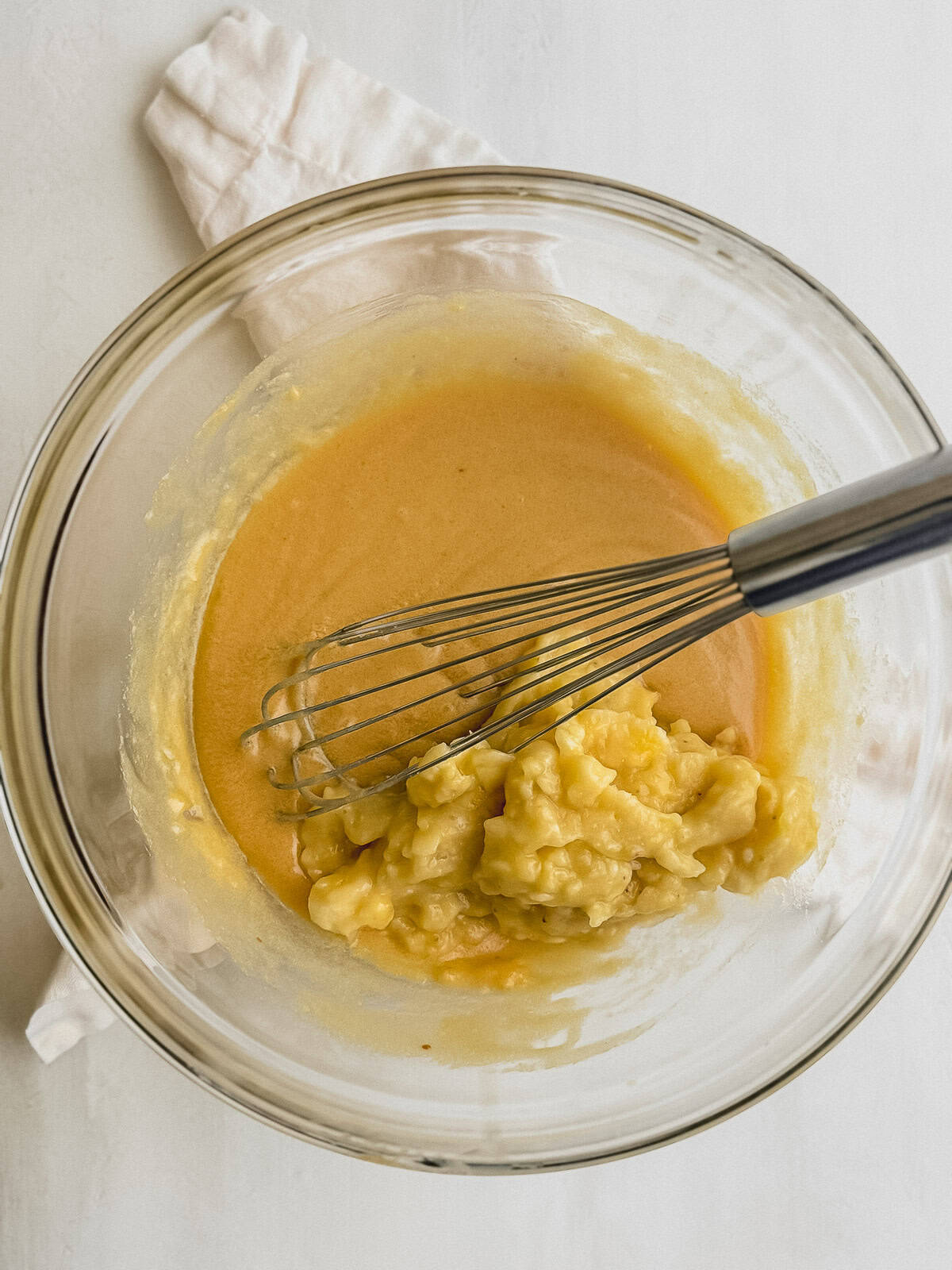 Mashed bananas in a glass bowl with banana bread batter.