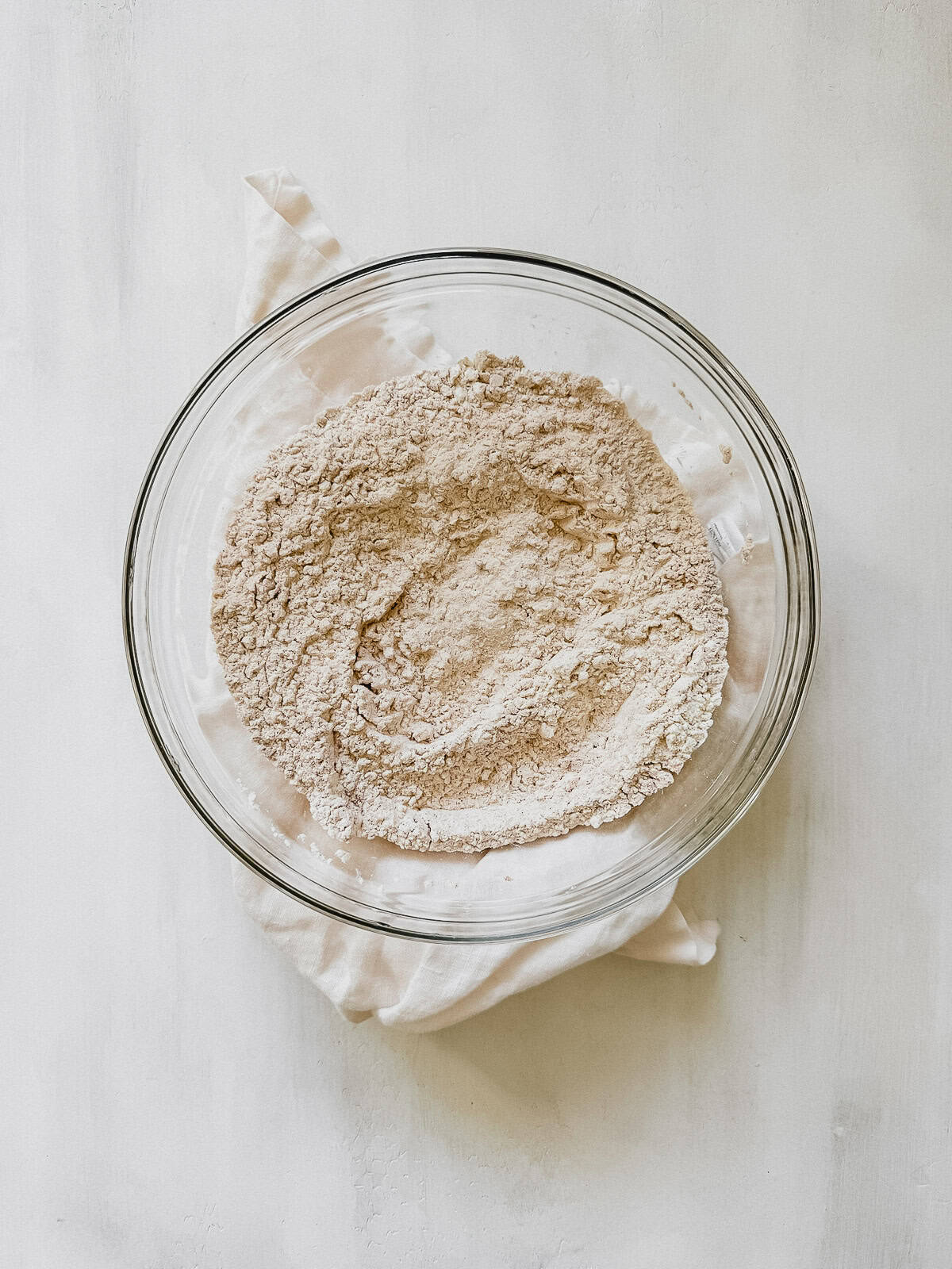 A mixing bowl with flour, baking soda, baking powder, salt, cinnamon, nutmeg, and pecans.