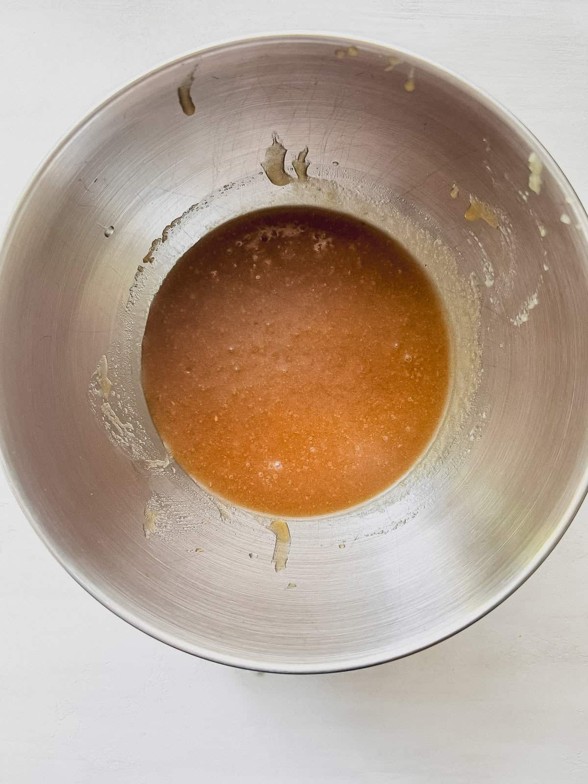 A mixing bowl with creamed vegetable oil, applesauce, and sugar.