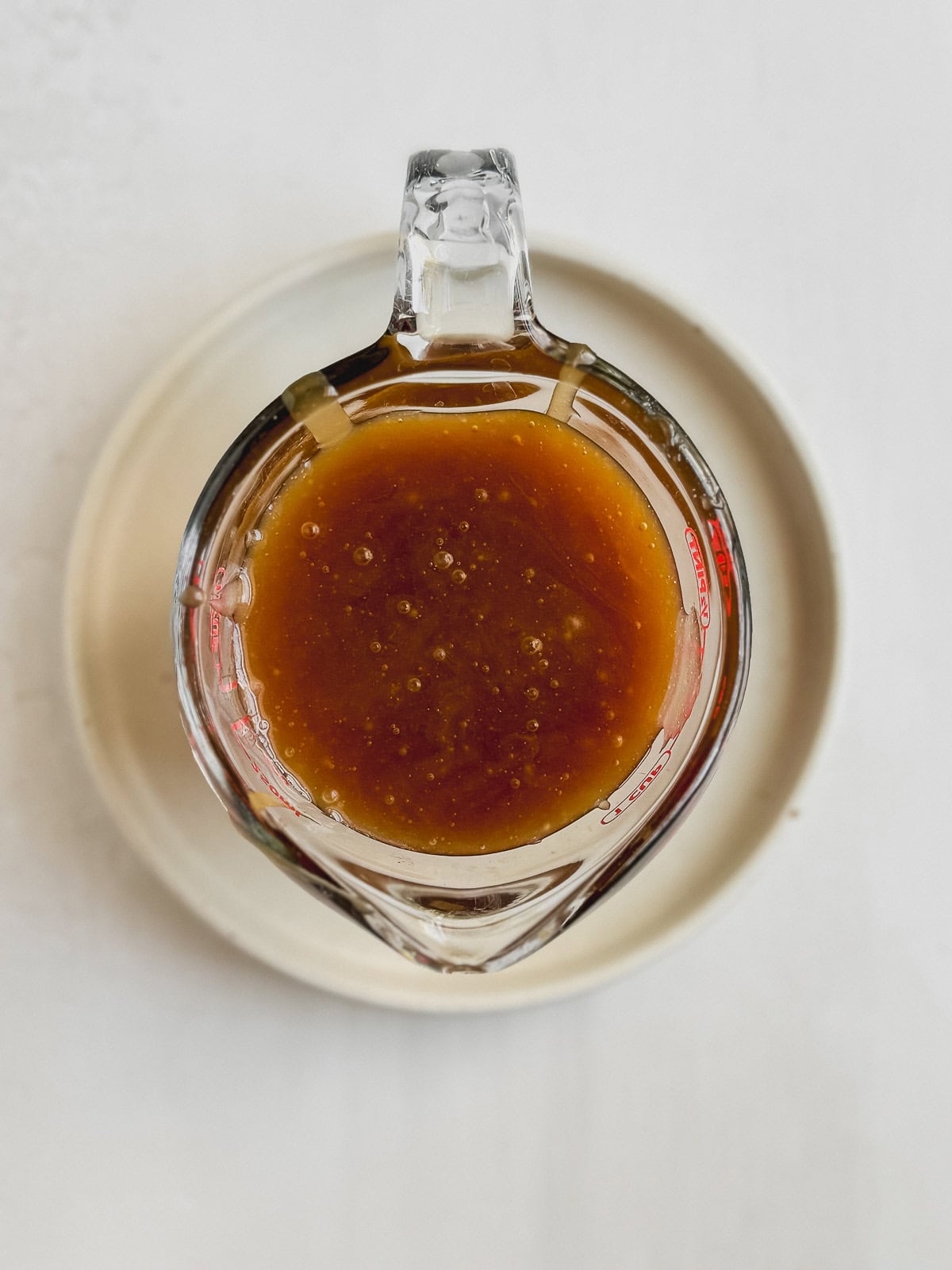 Caramel glaze in a small glass measuring cup.